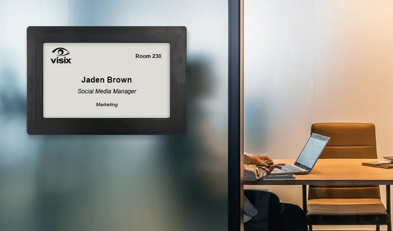 ePaper sign mounted on glass outside of shared office showing digital nameplate with reservation data