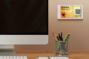 EPS 37 epaper sign showing desk reservation mounted on wall beside monitor and above cup of pencils